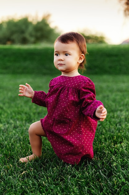 Portrait candide de petite fille debout sur l'herbe verte dans le parc