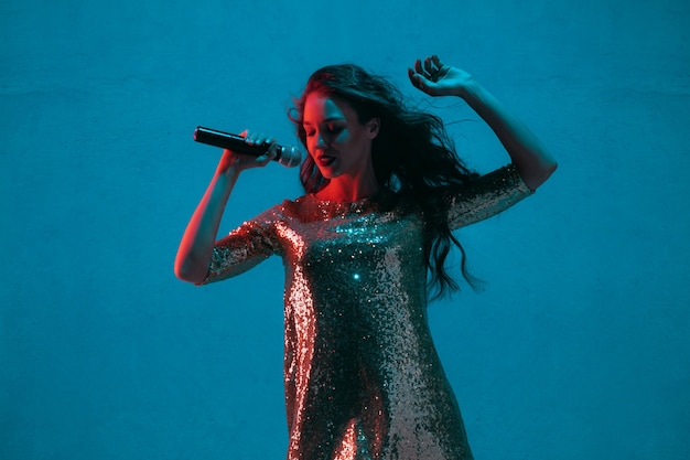 Portrait de chanteuse caucasienne isolé sur fond bleu studio en néon