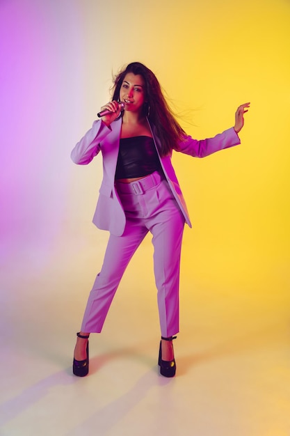 Portrait de chanteuse caucasienne isolé sur fond de studio dégradé à la lumière du néon