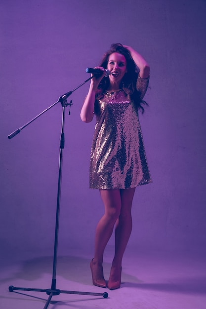 Portrait de chanteuse caucasienne isolé sur fond de studio violet en néon