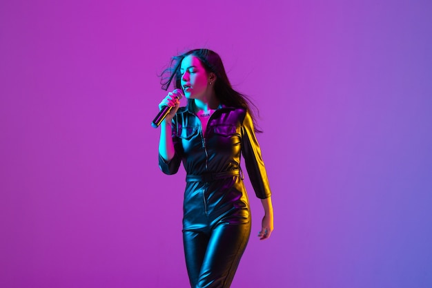 Portrait de chanteuse caucasienne isolé sur fond de studio violet en néon