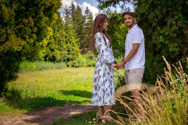 Portrait d'un charmant couple amoureux s'embrasse et se tient la main dans le jardin verdoyant