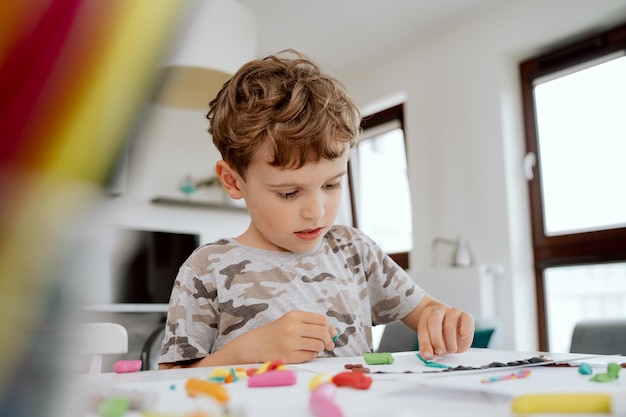 Portrait d'un charmant garçon d'âge scolaire heureux assis à la table de la cuisine profitant d'un peu de temps libre