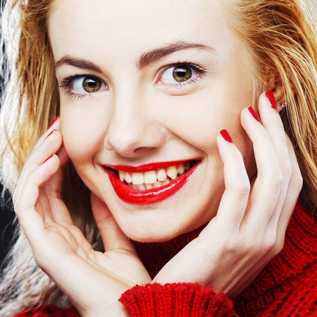 Portrait de charmante blonde souriante en pull rouge