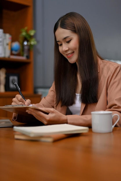 Portrait Charmante femme d'affaires asiatique notant quelque chose sur ses papiers