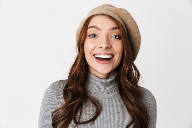 Portrait d'une charmante femme des années 30 portant un chapeau souriant et vous regardant isolé sur blanc