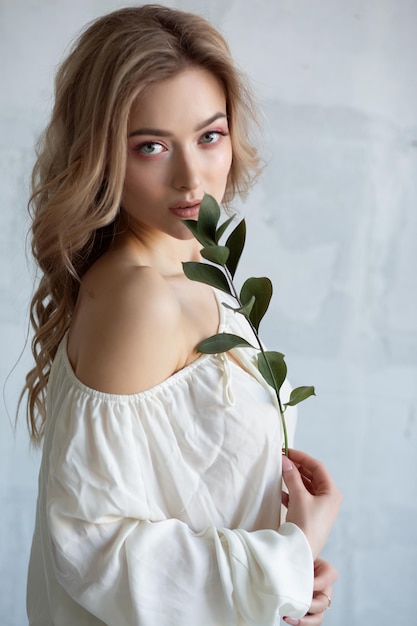 Portrait d'une charmante femme sexy dans un chemisier blanc avec une fleur dans ses mains