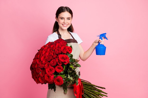 Portrait de charmante fille joyeuse tenant un grand bouquet de roses arrosant