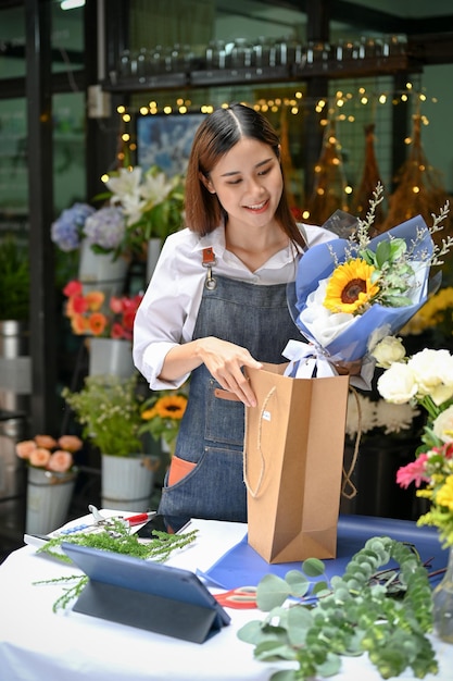 Portrait Charmante fleuriste asiatique préparant un bouquet de fleurs pour son client