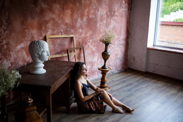 Portrait d'une charmante jeune femme aux cheveux bouclés fille à la peau claire dans un haut noir et avec un sourire sur son visage