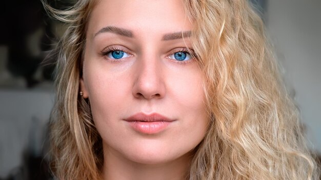 Portrait d'une charmante jeune femme souriante et séduisante aux cheveux blancs bouclés et aux yeux bleus à la recherche d'un