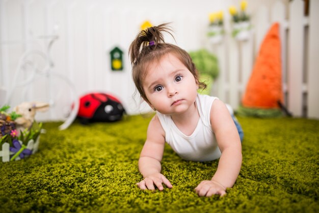 Portrait d'une charmante petite fille aux yeux bruns jouant sur un tapis dans une chambre d'enfants