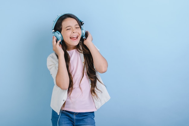 Portrait D'une Charmante Petite Fille Aux Yeux Fermés Dans Des écouteurs, écoutant De La Musique Et Chanter