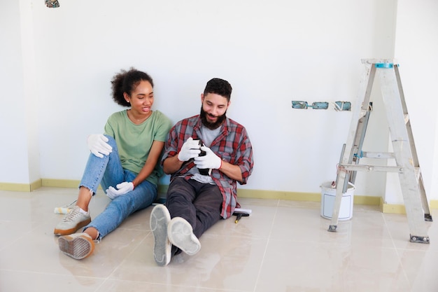 Photo portrait cheerful couple young man and black woman smiling pendant la rénovation dans un nouvel appartement