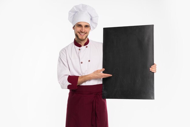 Portrait d'un chef cuisinier masculin gai en uniforme tenant un tableau blanc isolé sur fond blanc.