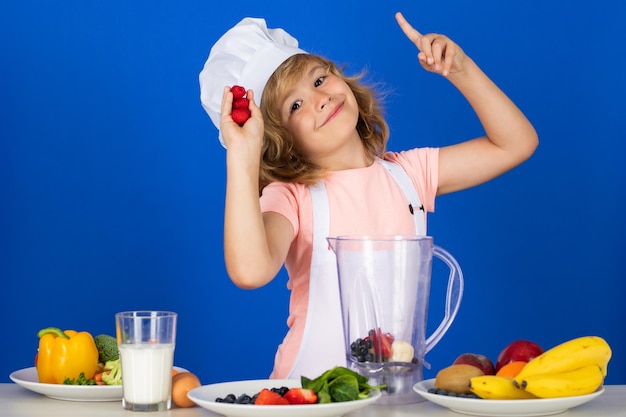 Portrait de chef enfant en chapeau de cuisinier cuisiner à la maison enfant garçon préparant un smoothie aux framboises de vegetab