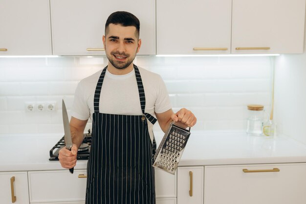 Portrait d'un chef homme tenant un couteau de cuisine et une râpe