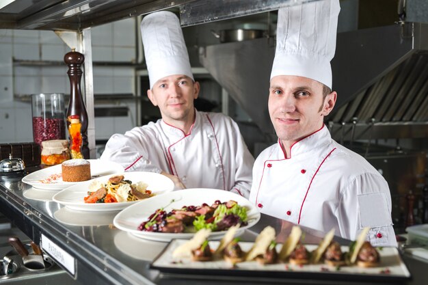 Portrait D'un Chef Avec Des Plats Cuisinés Dans La Cuisine Du Restaurant.