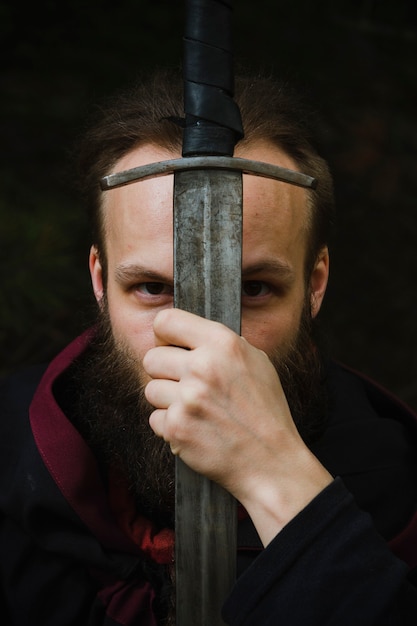 Photo portrait d'un chevalier tenant une épée au visage.