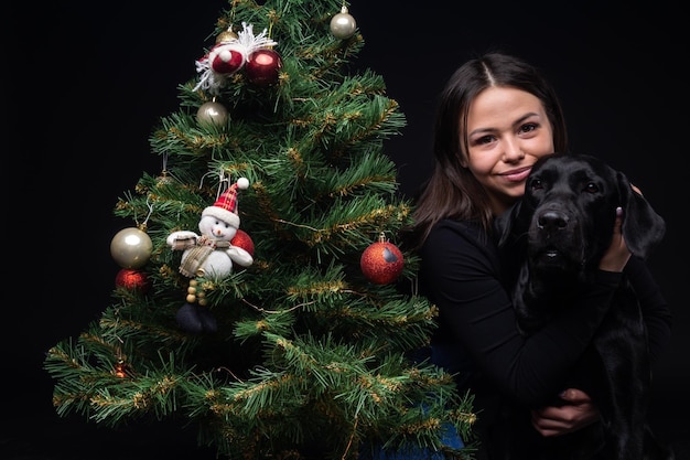 Portrait d'un chien Labrador Retriever avec son propriétaire près de l'arbre vert du nouvel an