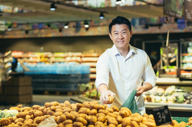 Portrait d'un client asiatique dans le rayon épicerie d'un supermarché un homme choisit des légumes et