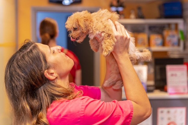 Portrait de la clinique vétérinaire d'une femme vétérinaire avec un petit chien se donnant un baiser