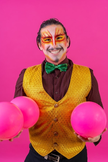 Portrait de clown avec un maquillage facial blanc sur fond rose balles de jonglage