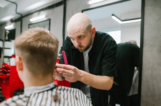 Le portrait d'un coiffeur professionnel crée une coupe de cheveux à la mode pour le client