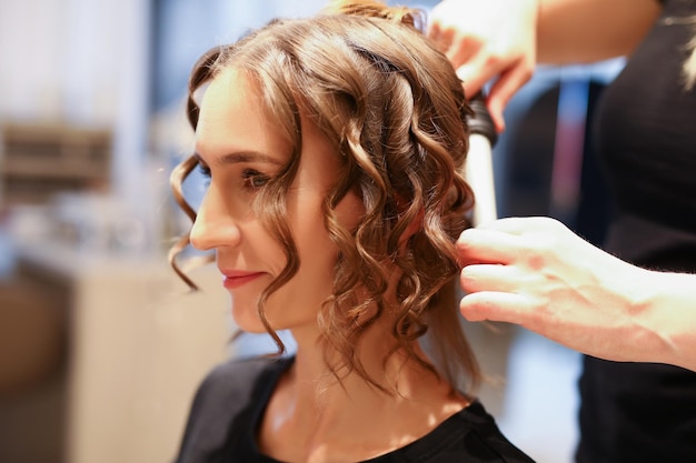 Portrait de coiffeur professionnel utilisant un fer à friser féminin créant un beau luxe