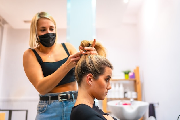 Portrait d'une coiffeuse dans un masque médical faisant son travail nouvelle normale