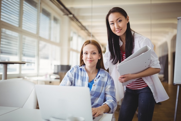 Portrait de collègues féminines travaillant sur ordinateur portable au bureau