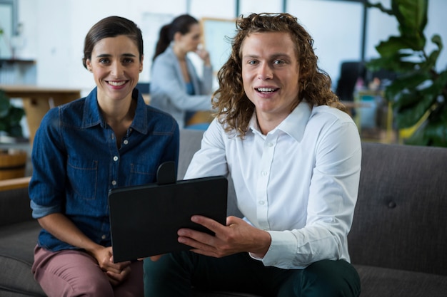 Portrait de collègues souriant discuter sur tablette numérique