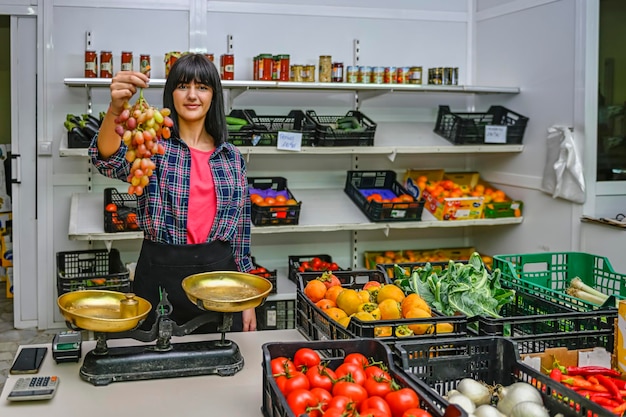 Portrait de commerçant chez le marchand de légumes montrant une grappe de raisins savoureux