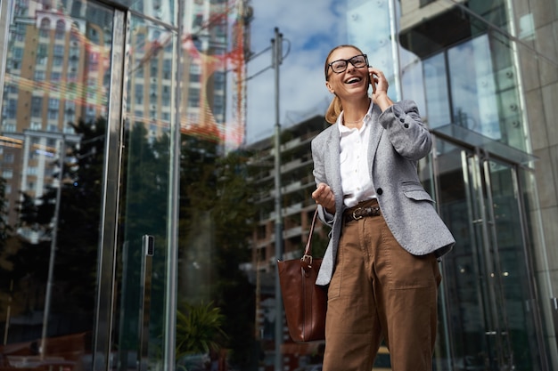 Portrait de communication d'une femme d'affaires à la mode heureuse portant des lunettes et des vêtements classiques