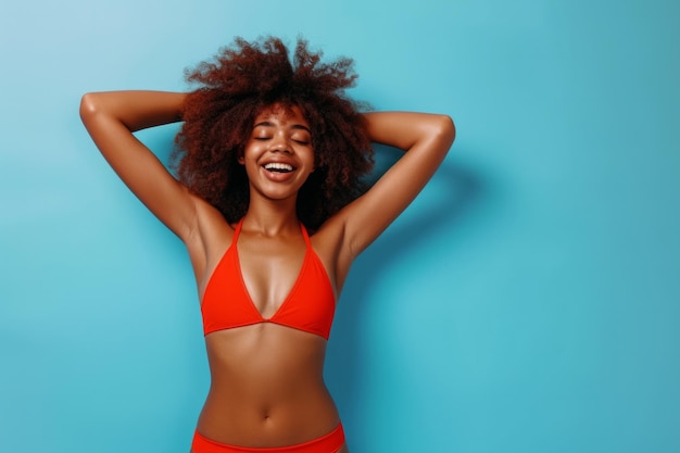 Portrait complet du corps d'une jeune femme afro-américaine heureuse et drôle en maillot de bain rouge qui part en vacances d'été et s'amuse sur un fond de studio bleu avec un espace de copie Concept de vacances et de voyage