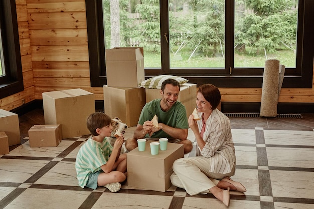 Portrait complet d'une famille heureuse dans une nouvelle maison en train de déjeuner avec un espace de copie de table de fortune