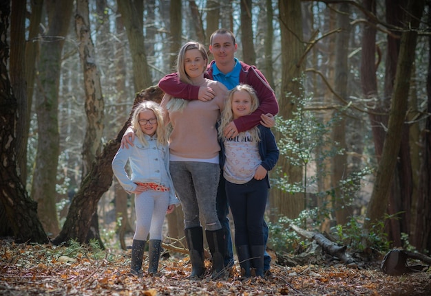 Portrait complet d'une famille heureuse debout dans la forêt