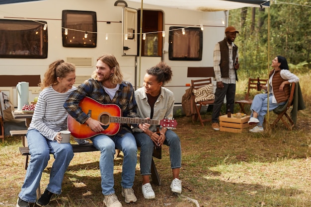 Portrait complet de jeunes heureux jouant de la guitare tout en profitant du camping en plein air avec sentier...