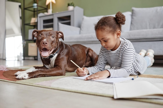 Portrait complet d'une jolie fille afro-américaine allongée sur le sol avec un gros chien, espace de copie