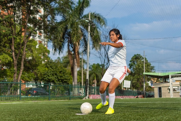 Portrait complet d'une joueuse de football latine sur le point de frapper le ballon Concept de joueur de football féminin