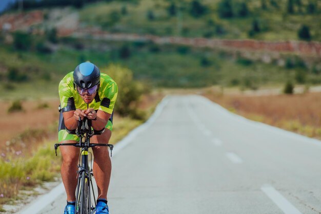 Portrait complet d'un triathlète actif en tenue de sport et avec un casque de protection faisant du vélo. Mise au point sélective.