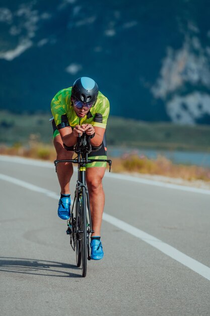 Portrait complet d'un triathlète actif en tenue de sport et avec un casque de protection faisant du vélo. Mise au point sélective.