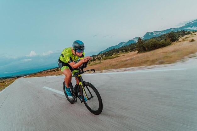 Portrait complet d'un triathlète actif en tenue de sport et avec un casque de protection faisant du vélo. Mise au point sélective.