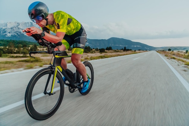 Portrait complet d'un triathlète actif en tenue de sport et avec un casque de protection faisant du vélo. Mise au point sélective.