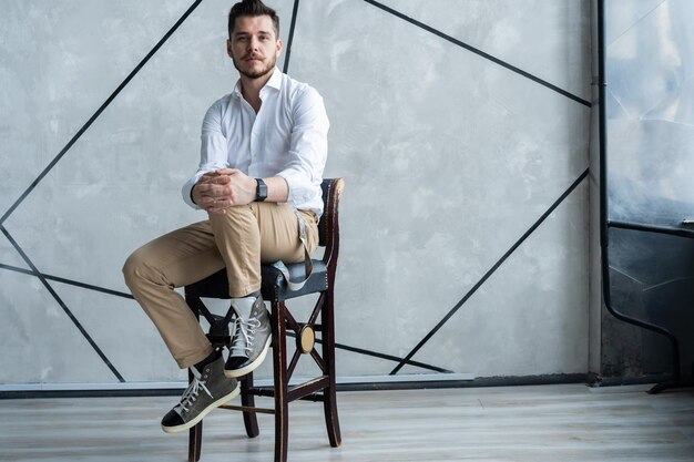 Portrait de confiance. Toute la longueur du jeune homme réfléchi en costume complet regardant loin alors qu'il était assis sur le tabouret.