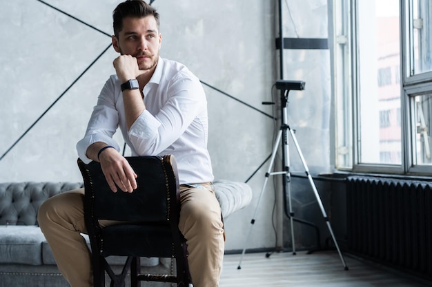 Portrait de confiance. Toute la longueur du jeune homme réfléchi en costume complet regardant loin alors qu'il était assis sur le tabouret.