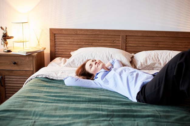 Portrait confortable d'une femme du millénaire se reposant sur un lit douillet Chambre à coucher avec un intérieur moderne