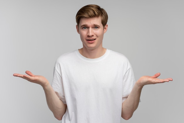 Portrait de confus beau jeune homme debout avec les bras levés