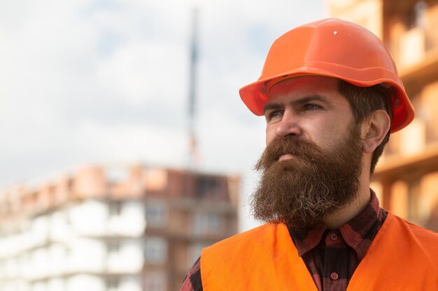 Portrait d'un constructeur de construction ouvrier constructeur en casque posant sur un chantier de construction