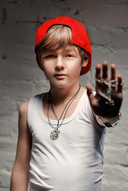 Portrait de cool jeune garçon hip hop en chapeau rouge et pantalon rouge et chemise blanche dans le loft